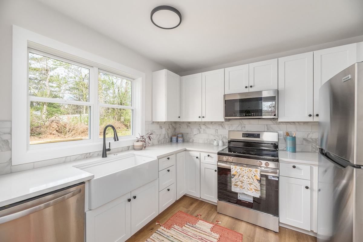 Kitchen with white shaker cabinets, farmhouse sink and new stainless appliances