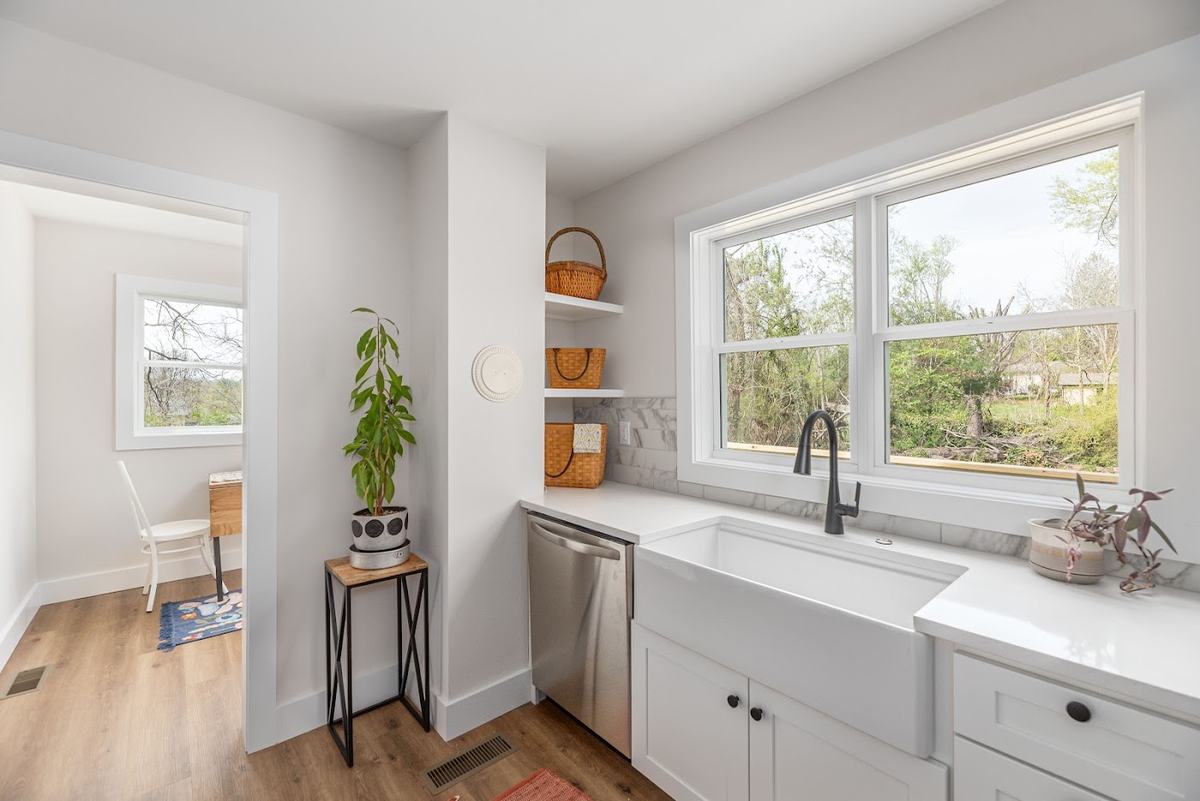 Farmhouse sink under a double window with open shelving