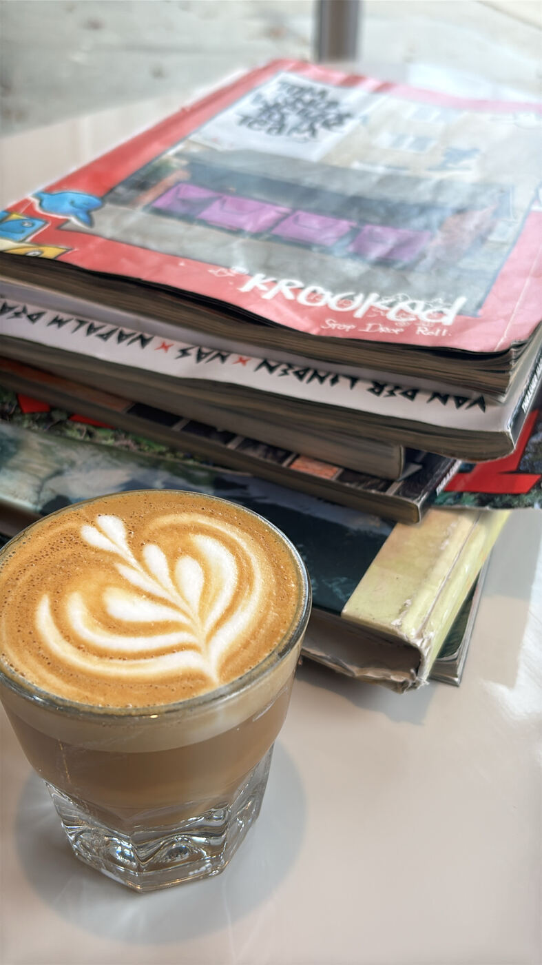 A cortado with latte art on a stack of magazines at an Asheville coffee shop