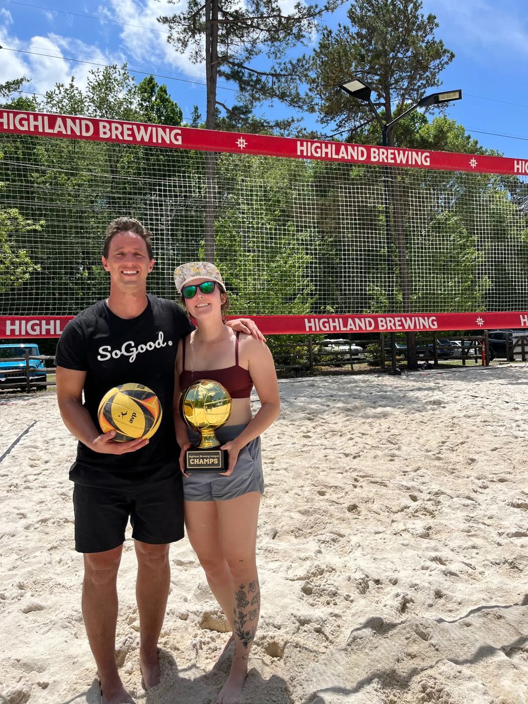 Dylan Lennon holding a Highland Brewing League Champs trophy after a beach volleyball match